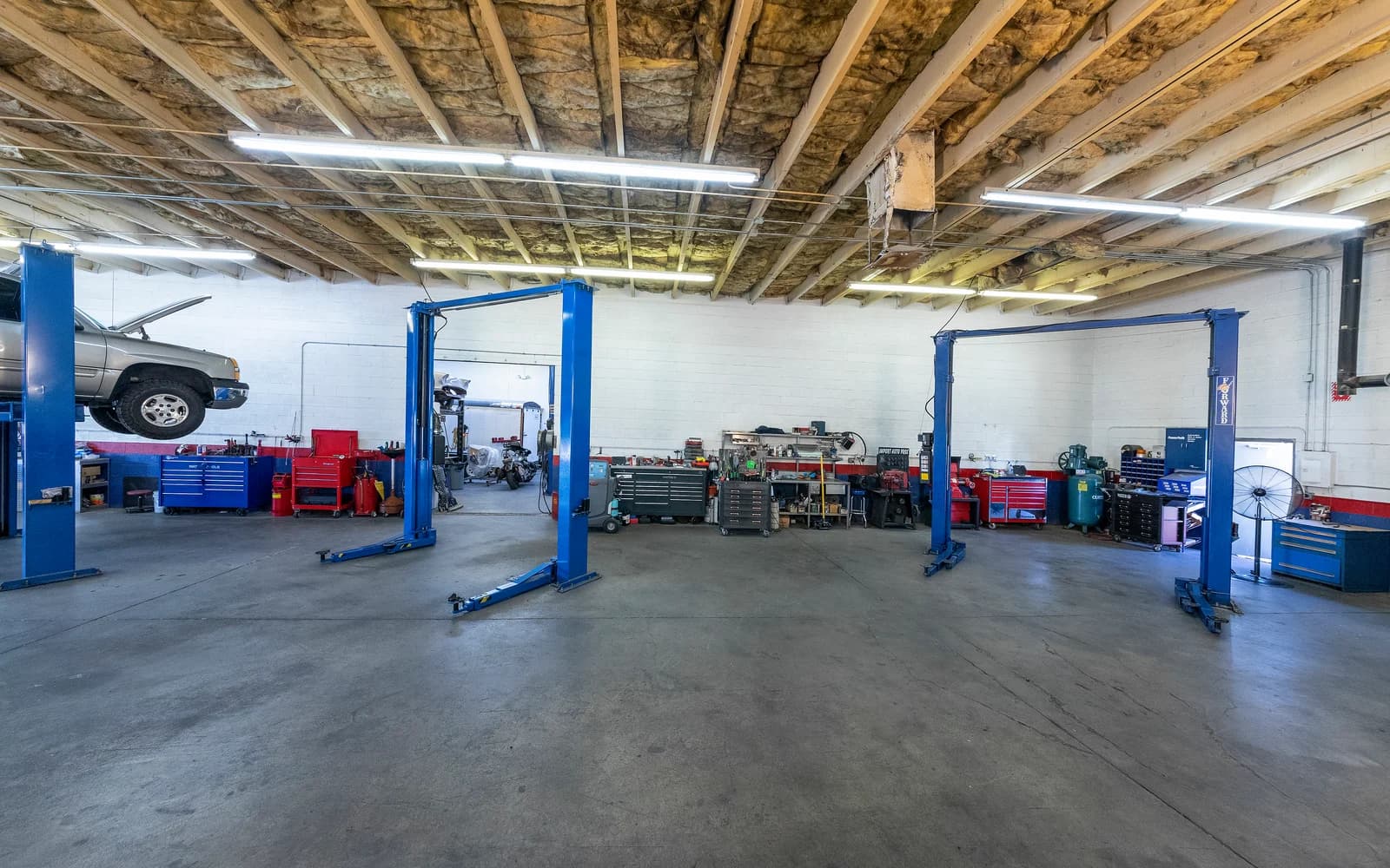 Open shop floor at Import Auto Pros with two-post lifts and tool chests along the far wall