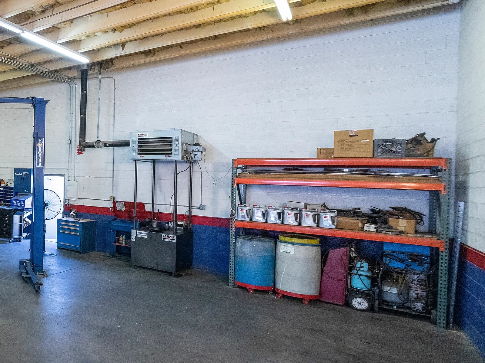 Wall heater above shelves of parts, cans and drums in a service bay