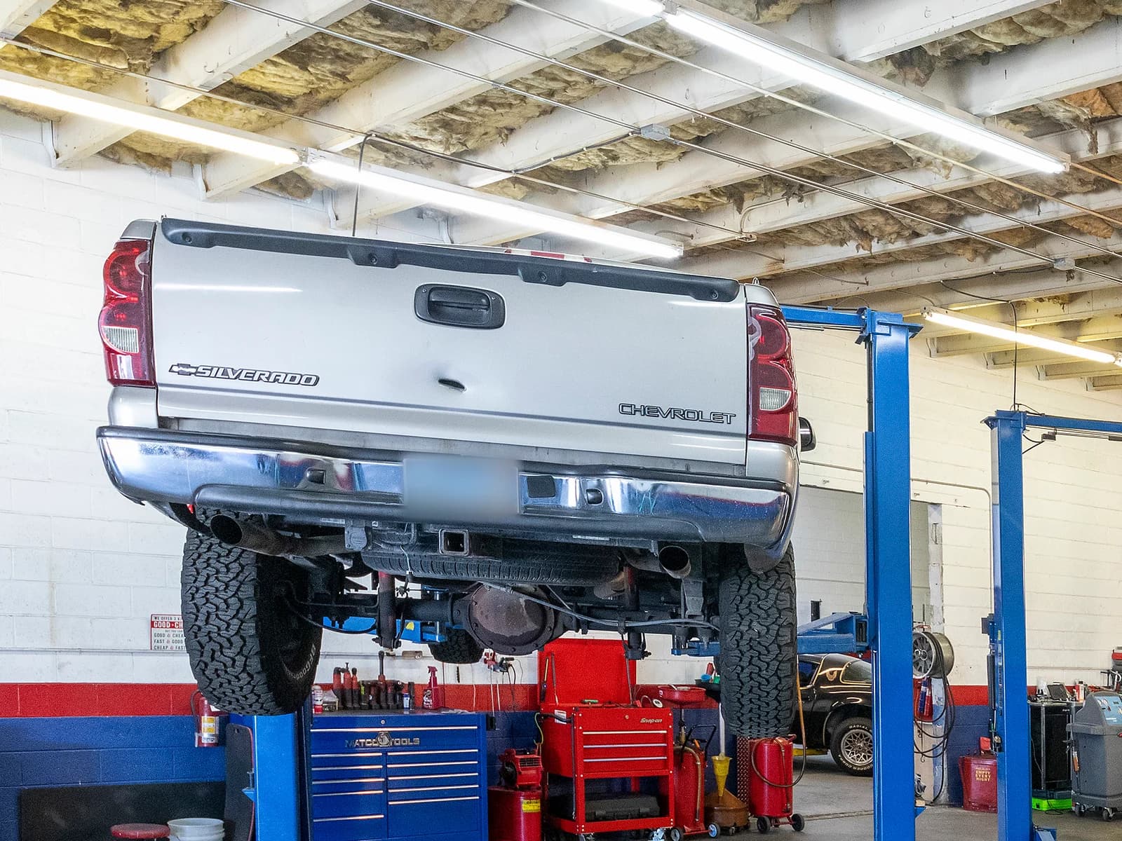 Underside, rear axle and wheels of a pickup truck raised high on a two-post lift