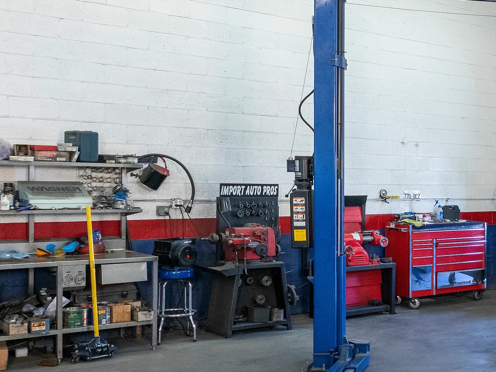 Workbench with tools, a stool and a red tool chest beside a lift post