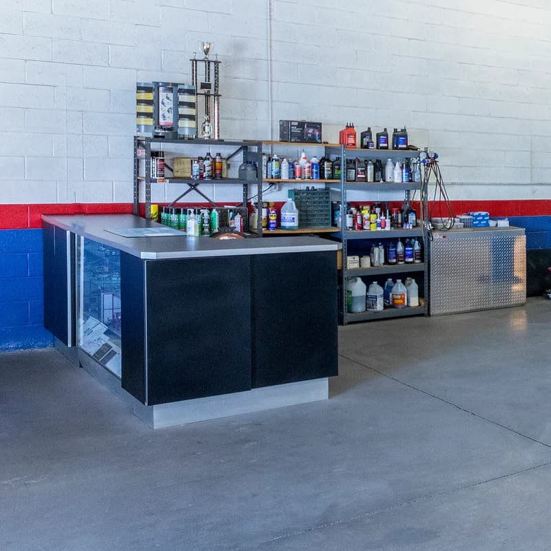 Glass-fronted service counter with shelves of fluids and products behind it